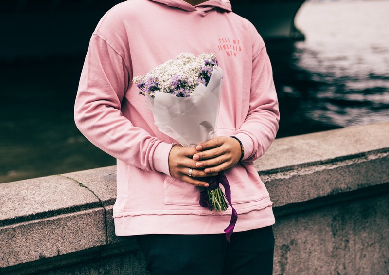 a woman in a pin hoodie wearing a wedding ring holds a bouquet, valentines day 4k