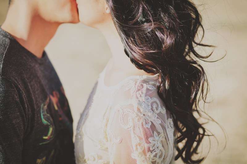 young woman with lacey dress and hair blowing in wind kisses her boyfriend, young love in summer 4k