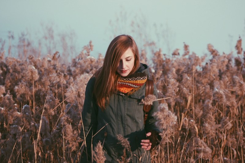 a redheaded woman wearing a winter coat and red scarf standing in a field, woman in field 4k