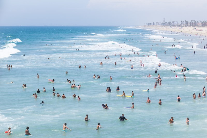 huntington beach filled with swimmers surfers and people on the shore, huntington beach crowded with people 4k