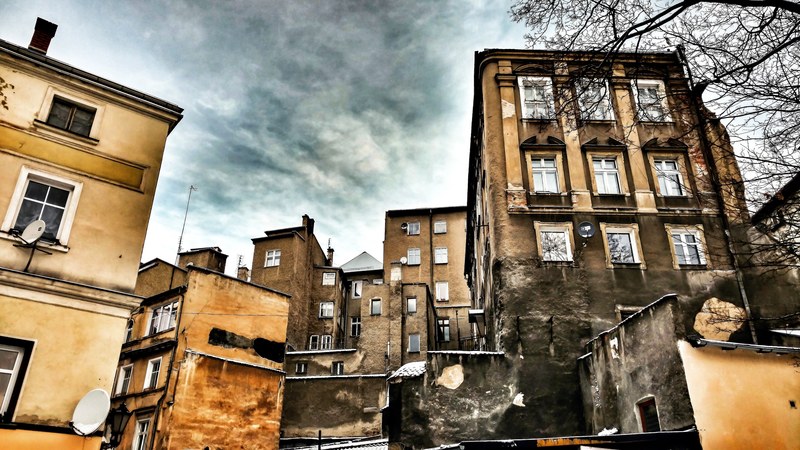 a group of old apartment buildings with fire damage and gray clouds in the background, _asymmetric district 4k