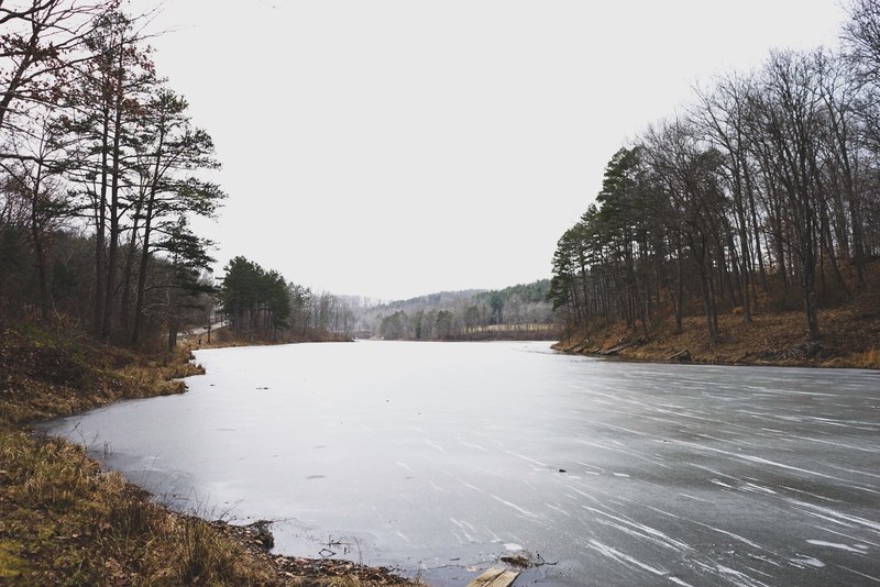 a small frozen lake under pale white sky, frozen lake in winter 4k