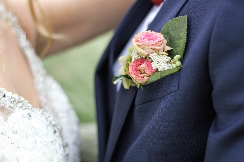 a small bouquet of roses and tiny white flowers in the buttonhole of a grooms suit, buttonhole flowers 4k