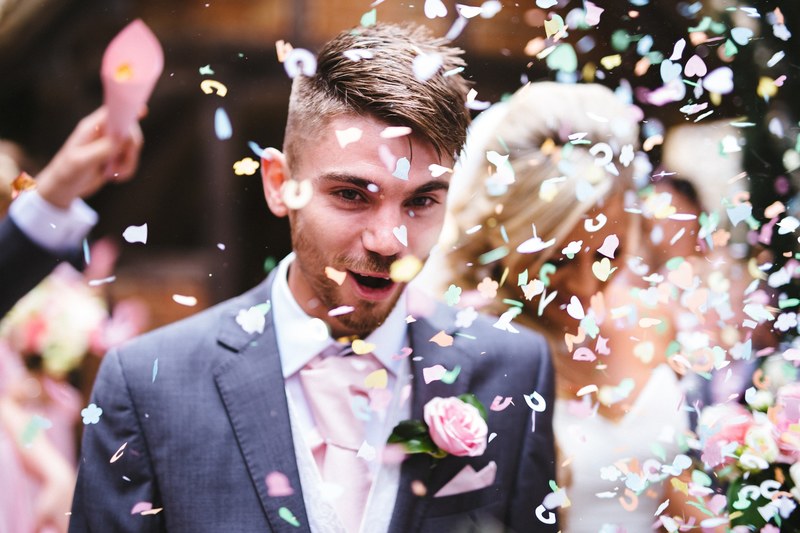confetti is thrown over excited groom leading the way for bride after ash vale wedding, confetti on groom at ash vale 4k