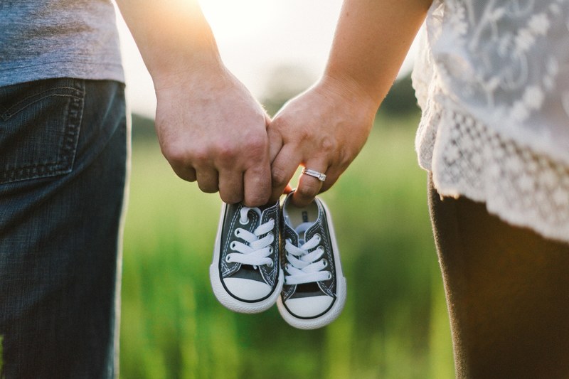 couple outdoors holding baby shoes in clasped hands, baby shoes 4k