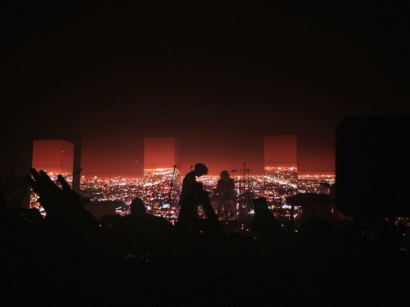 dark concert venue with silhouetted audience and band in front of red cityscape, the 1975 4k