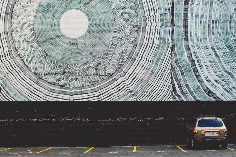 mural in a los angeles with single car parked in parking lot, rings 4k