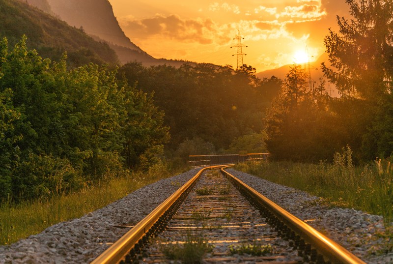 a curve in a railway track running under serene woody hills during sunset, railway curve at dusk 4k