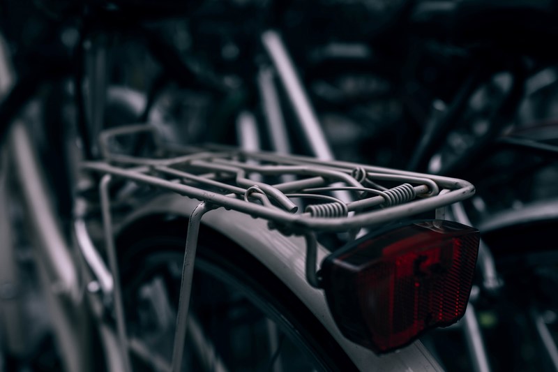 macro of a bikes rear red light and seat over rear bicycle beside various other bikes, bike seat 4k