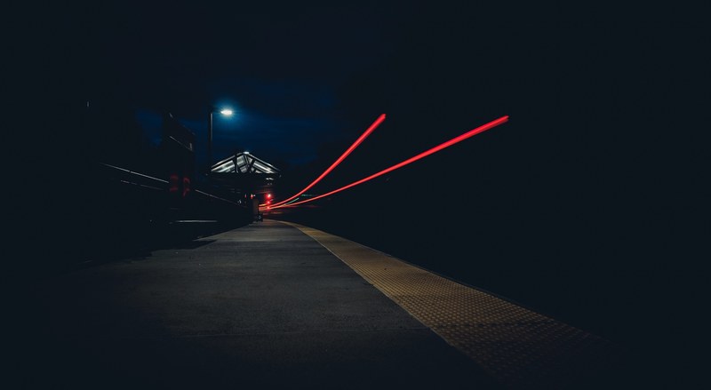 a night time shot displaying two mysterious red light trails and a dim streetlight, two red light trails at night 4k
