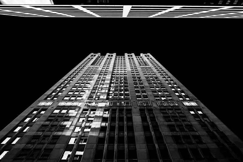 black and white shot of skyscraper from below at night with windows and reflection, monochrome skyscraper shot 4k