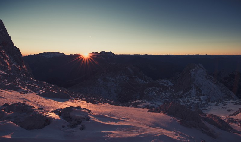 sun low in the horizon overlooking mountainous winter landscape at mangart, mountainous winter landscape at mangart 4k