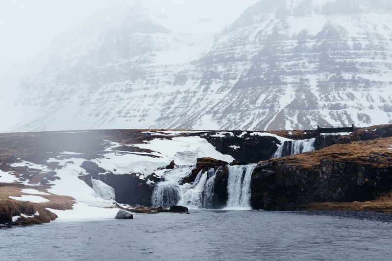 small waterfalls feed into a lake at the foot of a snowy mountain, waterfalls at snowy mountain 4k
