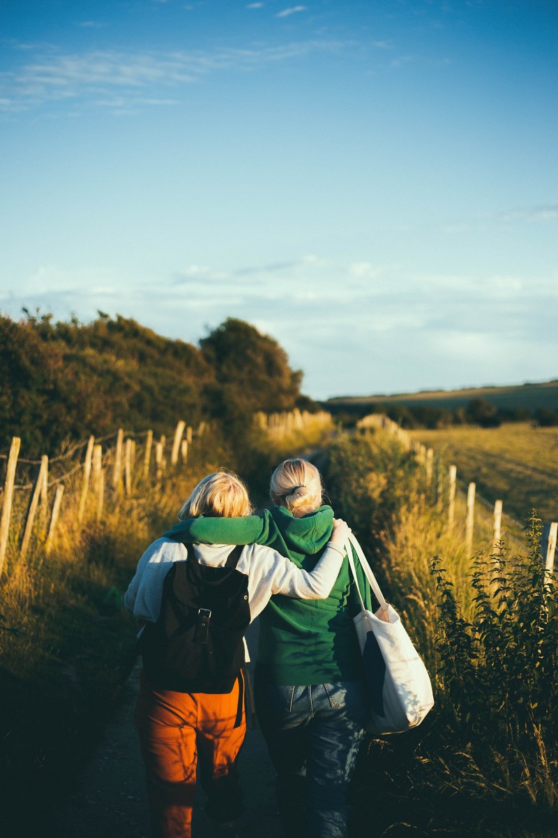 friends with arms wrapped around each other walk together, side hug 4k