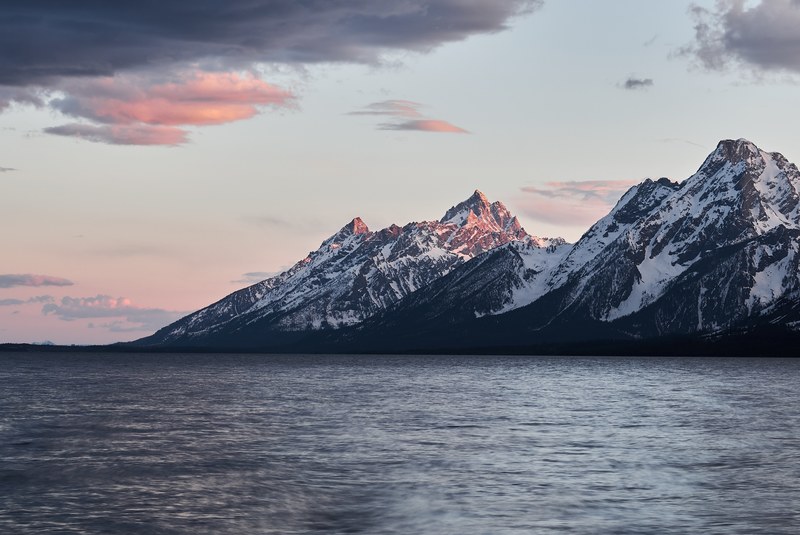 view from a lake on the snow capped mountain peaks on the shore, grand tetons 4k