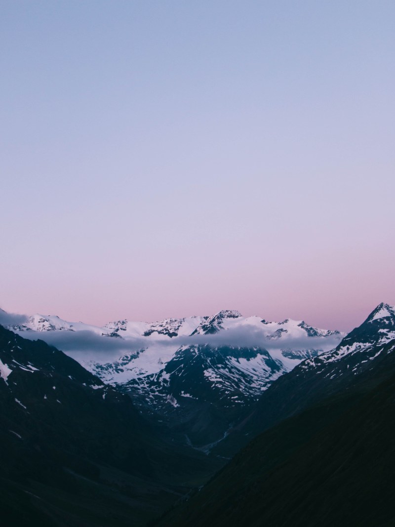the top of snowy mountains under a light blue and violet sky, mountains under violet sky 4k