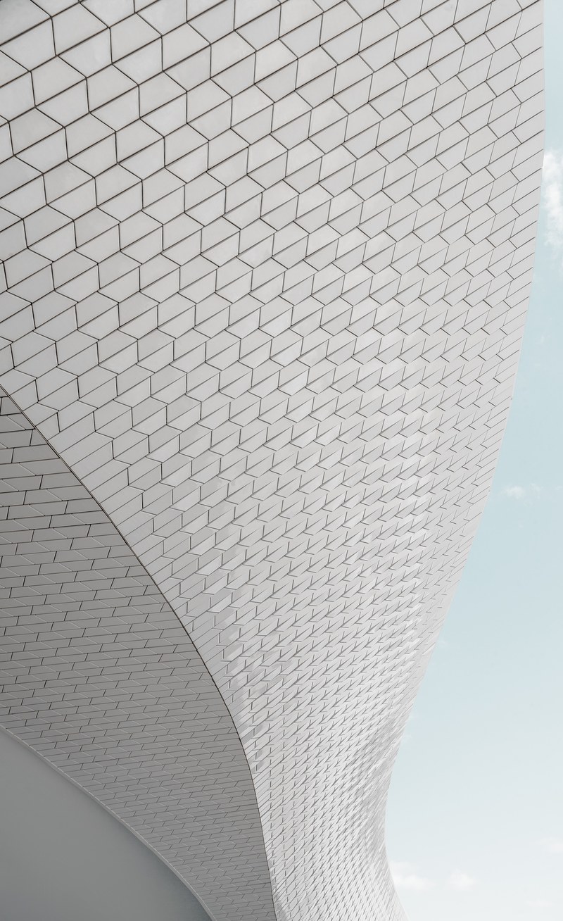 a long curving white facade against a pale blue sky, minimal white curving facade 4k