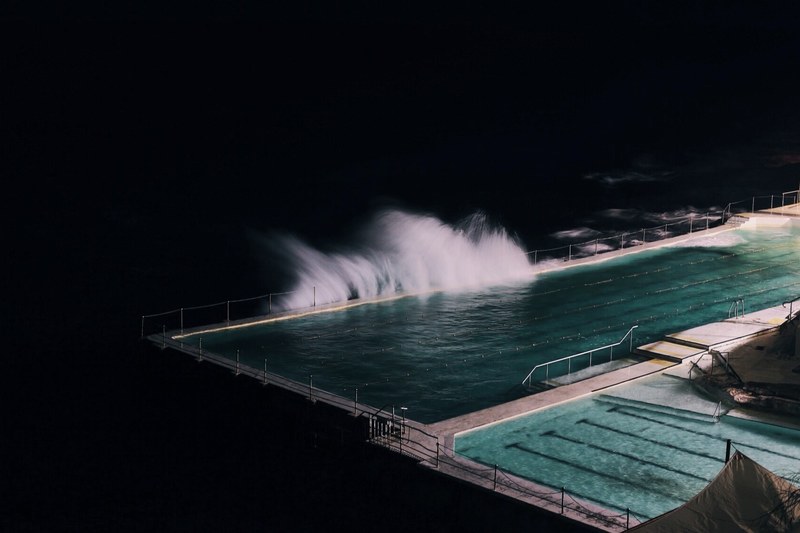 bondi beach at night with waves from the ocean splashing into it, bondi beach pool 4k