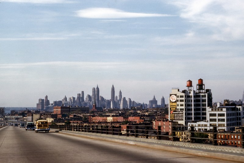 old cars driving on a road leading to new york with city skyline on the horizon, vintage cars on a road to new york 4k