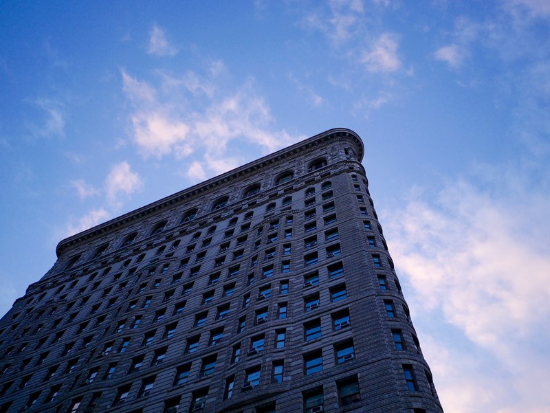 as the sun sets a city apartment building cuts out a majestic edge against the sky, long shadowed apartment building 4k