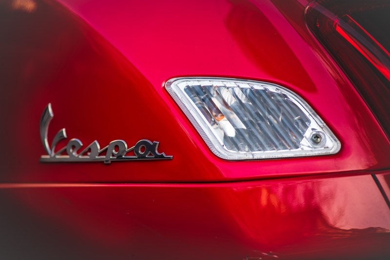 macro of a vespa logo on a red automobile, vespa logo on a motor vehicle 4k