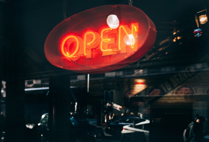 a red neon open sign over the storefront in soho, open for business 4k