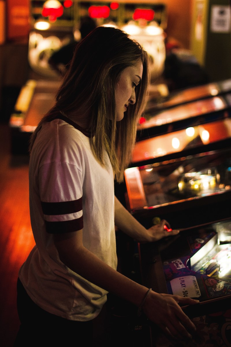 a woman with medium length brown hair plays a game in an arcade, woman playing arcade game 4k