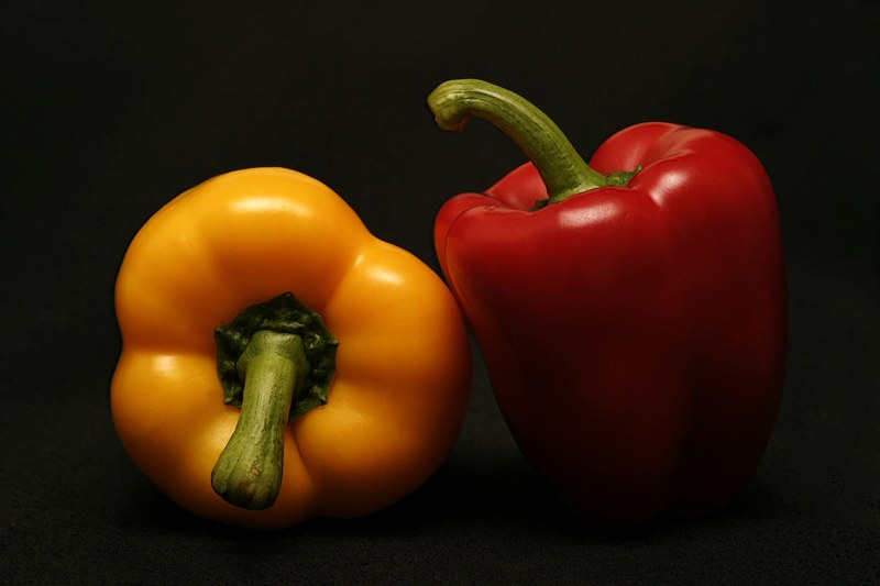 red and yellow bell peppers in the shadows against a black background, fresh sweet peppers 4k