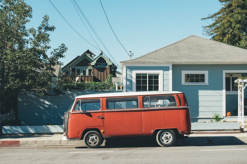 vintage red volkswagen van parked on the street in front of a light blue house, red and blue 4k