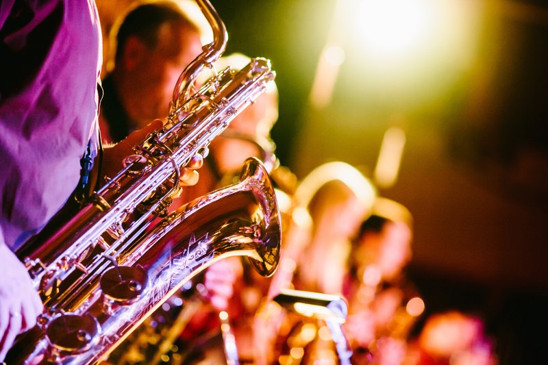 a close up of a saxophone held by one of the band members during a jazz concert, colorful jazz concert 4k