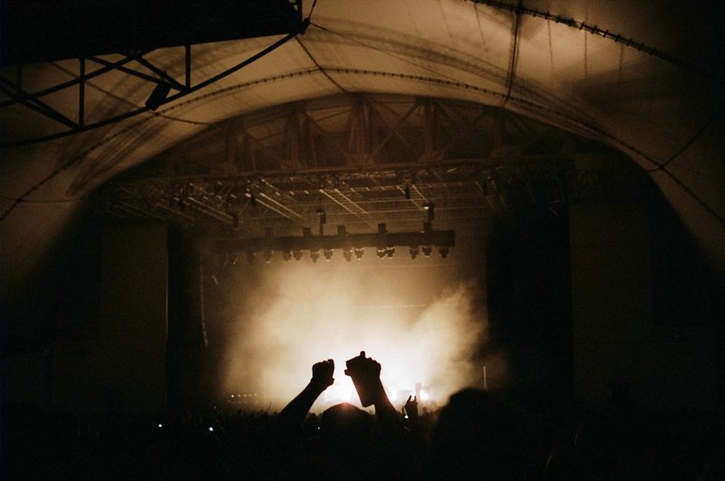 silhouettes of the audiences hands in the air during a concert, silhouettes against pale stage smoke 4k