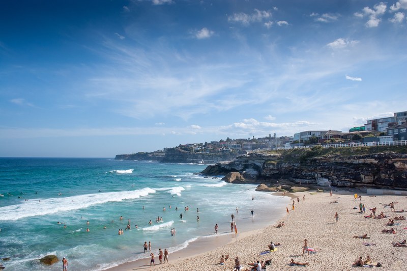 people having fun swimming in the blue ocean and relaxing on the beach shore on a summer day, people enjoying summer beach 4k