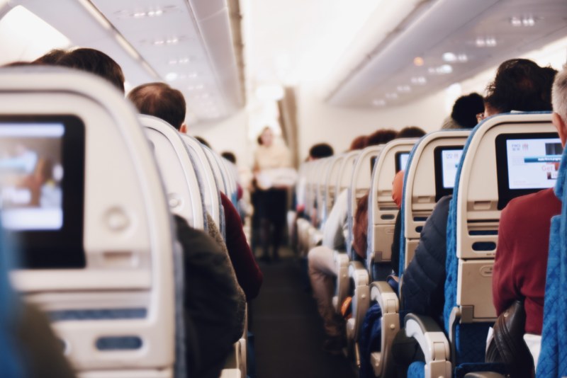 a view of the airplane aisle with a flight attendant carrying a tray, airplane aisle during flight 4k
