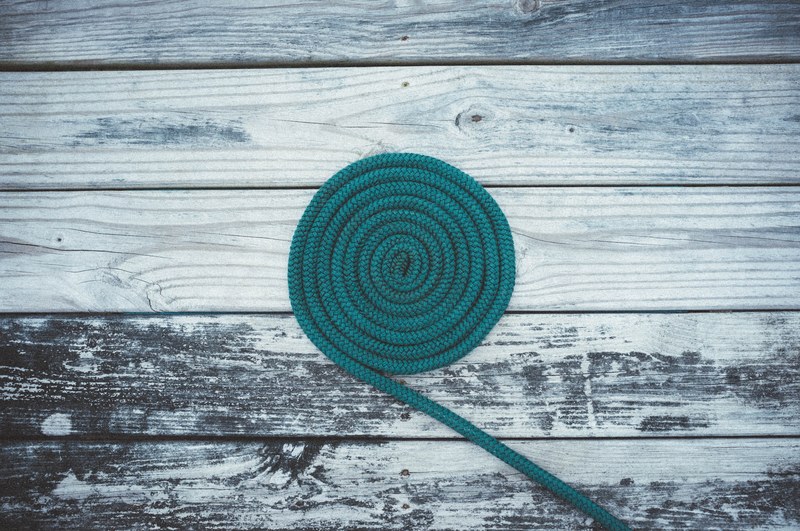 a green rope shaped like a coil on top of a wooden deck, rope coil on deck 4k