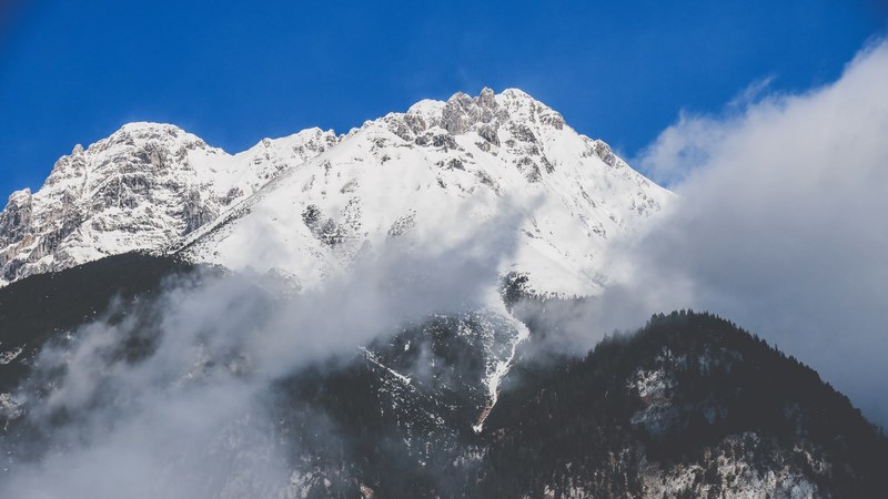 a sharp cloud shrouded peak against a blue sky in innsbruck, day 21 unsplashdaily 4k