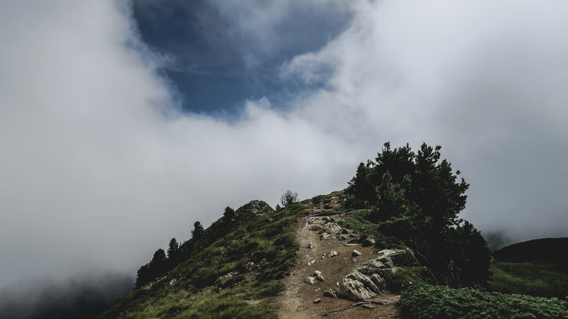 rocky hiking path on a grassy hillside leads to clouds, hike to the sky 4k