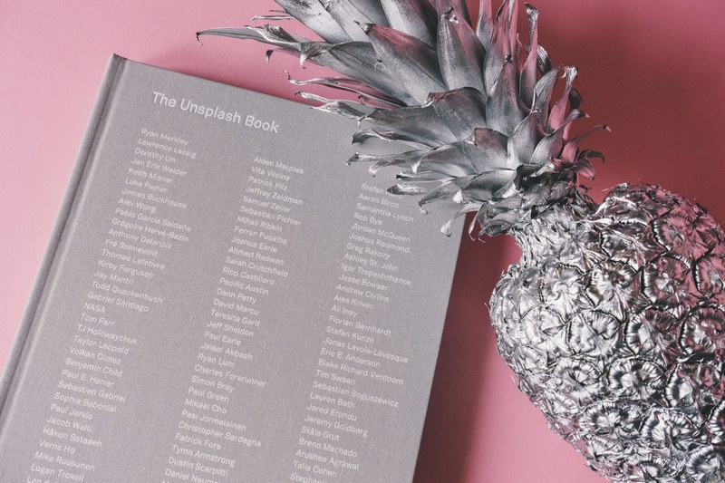 a gray painted pineapple next to a gray hardback book, _gray pineapple 4k