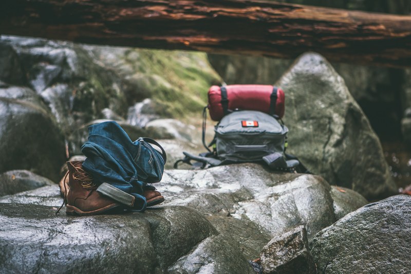 a backpack sleeping bag jeans belt and hiking boots on a rock in cypress falls park, hiking gear cypress falls 4k