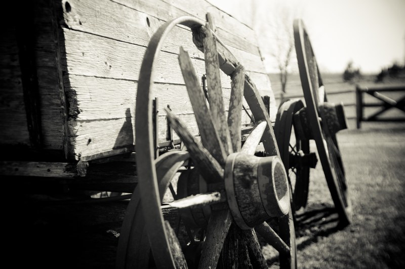 black and white close up shot of wooden wagon wheels with wooden fence in background, monochrome wooden wagon 4k