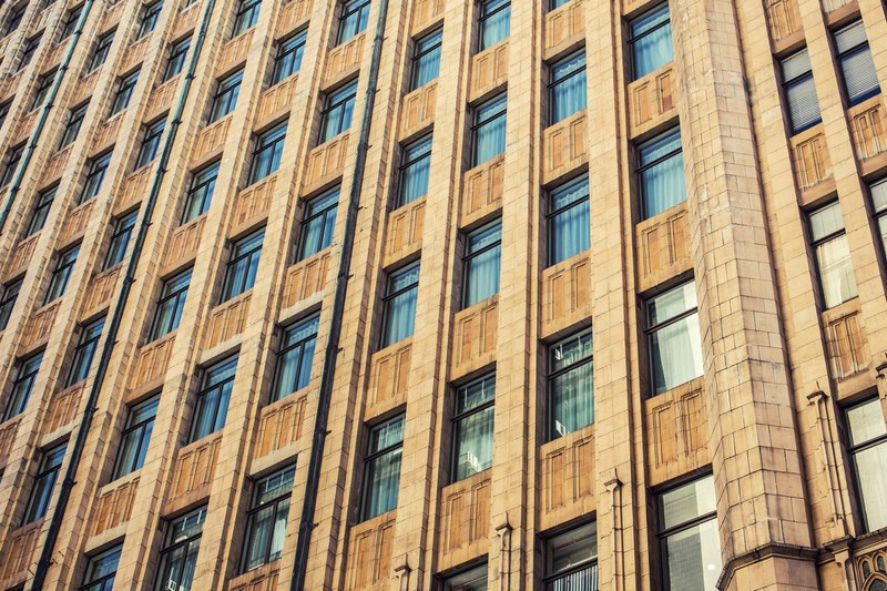 facade of apartment building in the city with brown exterior and reflective windows in a pattern, brown apartment building 4k