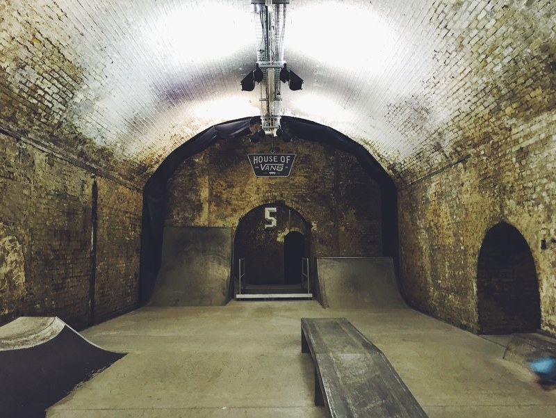 old tunnel with bricks walls and domed ceiling converted into a skateboarding room complete with ramps and lights, lit skateboarding tunnel 4k