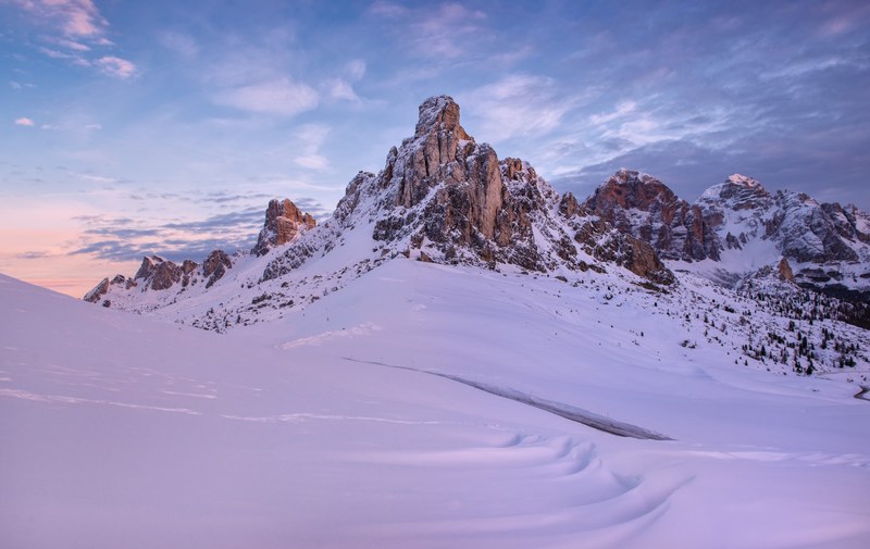 a snow covered mountain base and a mountain peak touching blue skies, snowy mountain peaks touch the sky 4k