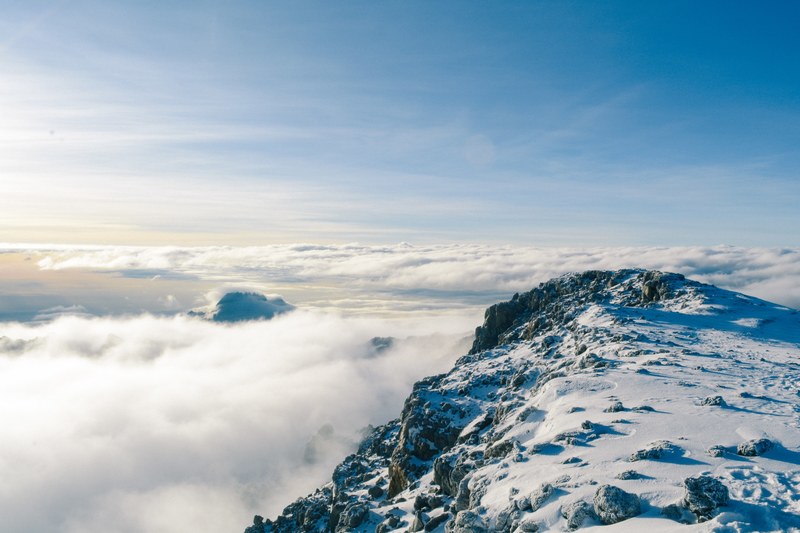 big white clouds hovering by snowy mountain top with blue open sky ahead, snowy mountains in sky 4k