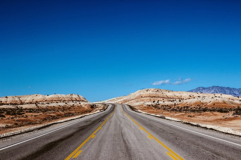 a desert road that goes to the horizon on a day with blue skies, highway horizons 4k
