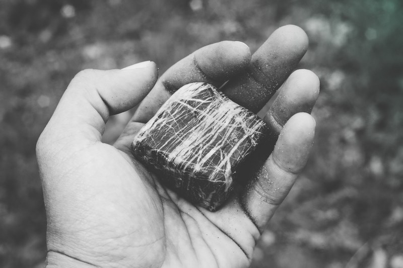 a black and white photo of a persons hand holding a cube shaped rock, black and white rock cube 4k