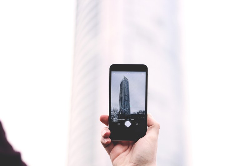 a person taking a picture of a skyscraper with a phone, photographing a skyscraper 4k