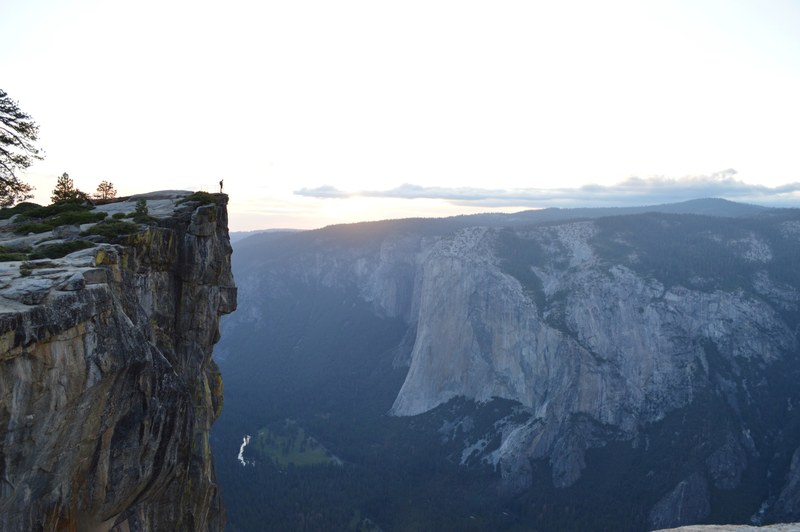 a silhouette of a man standing on a rocky ledge and looking into the breathtaking yosemite valley, precipice over yosemite valley 4k