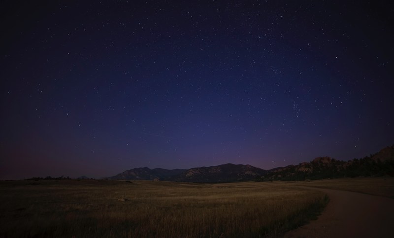 a country road with mountains in the distance under a starry night in colorado, _country road colorado 4k