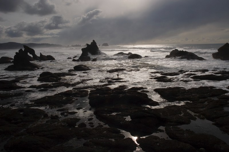 person standing on the rock while rough ocean is splashing the rocky coast at shi shi beach, rough ocean splashing coast 4k