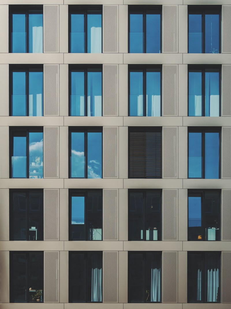 a modern facade of a building in cologne with floor to ceiling windows, modern gray facade in cologne 4k